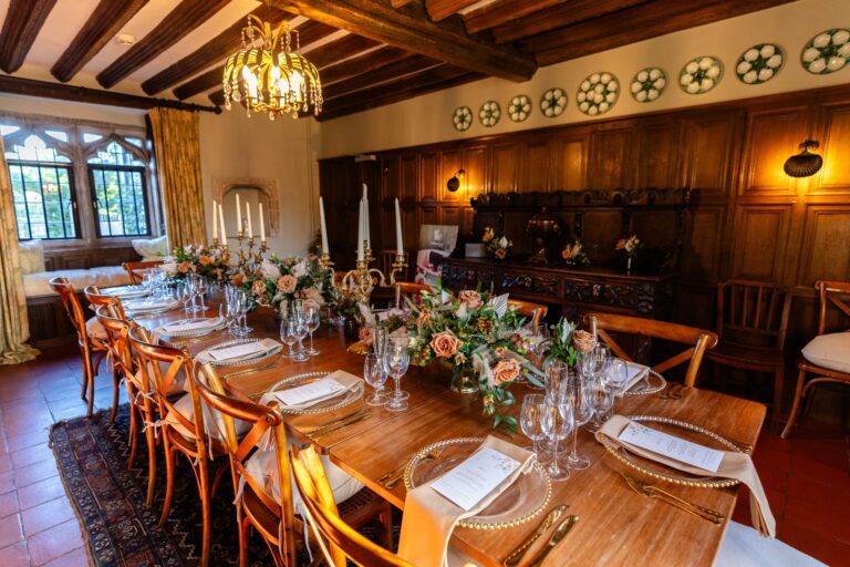The oak-panelled dining room at Battel Hall laid for a small wedding dinner, with candles and peach roses, Leeds Castle