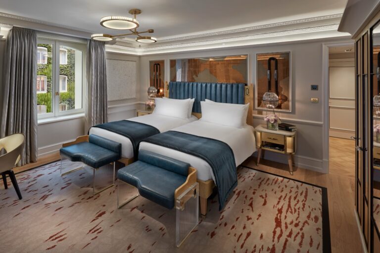 A twin bedroom with blue upholstered bed ends, panelled walls and a chandelier, Mandarin Oriental Hyde Park