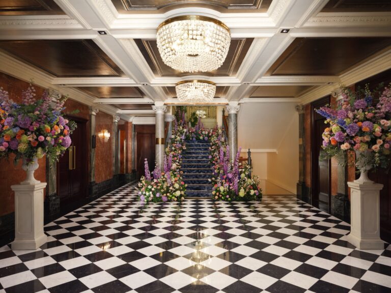 A black and white marble hall with crystal chandeliers and large floral arrangements at the foot of a staircase, Mandarin Oriental Hyde Park