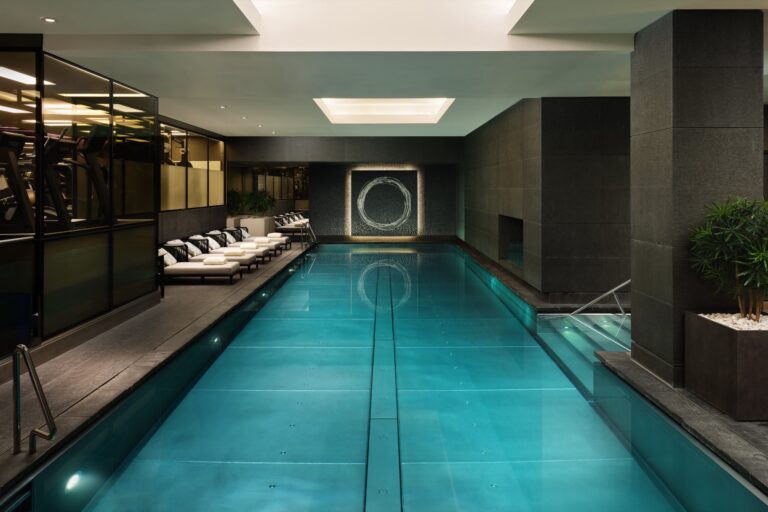 The indoor pool, a long lit lane of water between dark stone walls with loungers at the far end, Mandarin Oriental Hyde Park