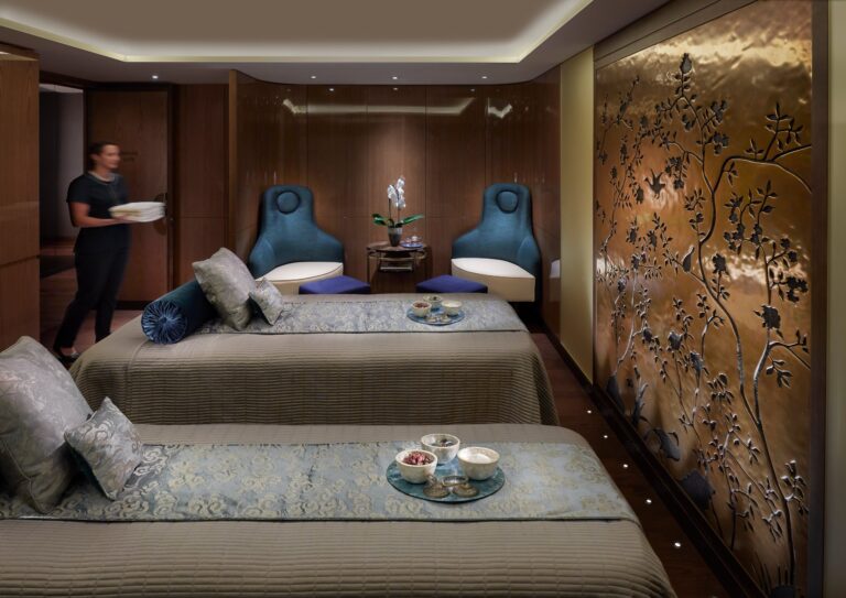 A couples treatment suite with two massage beds and a gold patterned wall panel, Mandarin Oriental Hyde Park