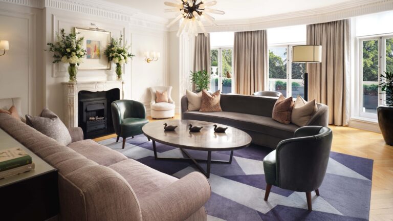 A suite living room with a fireplace, curved sofas and a round coffee table, Mandarin Oriental Hyde Park