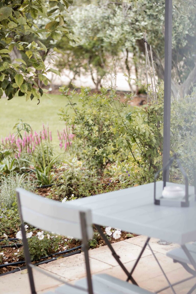 A room patio opening onto planted borders and lawn, Masseria Don Luigi