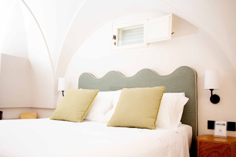 Bed with a wavy green headboard under the vault, Standard Attic Room, Masseria Don Luigi