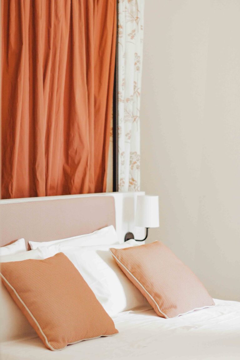Bed with terracotta cushions beside a curtained window, Superior room, Masseria Don Luigi