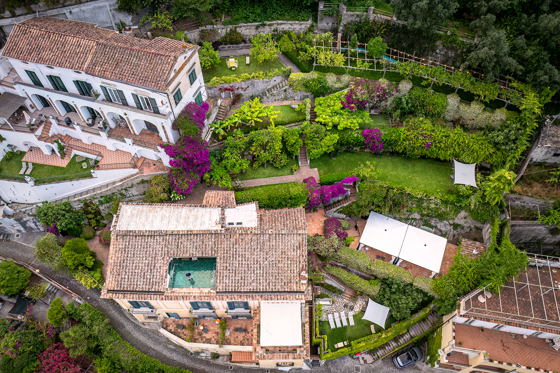 Aerial view of the palazzo buildings and terraced gardens with lawns, bougainvillea and white shade sails, Palazzo Suriano