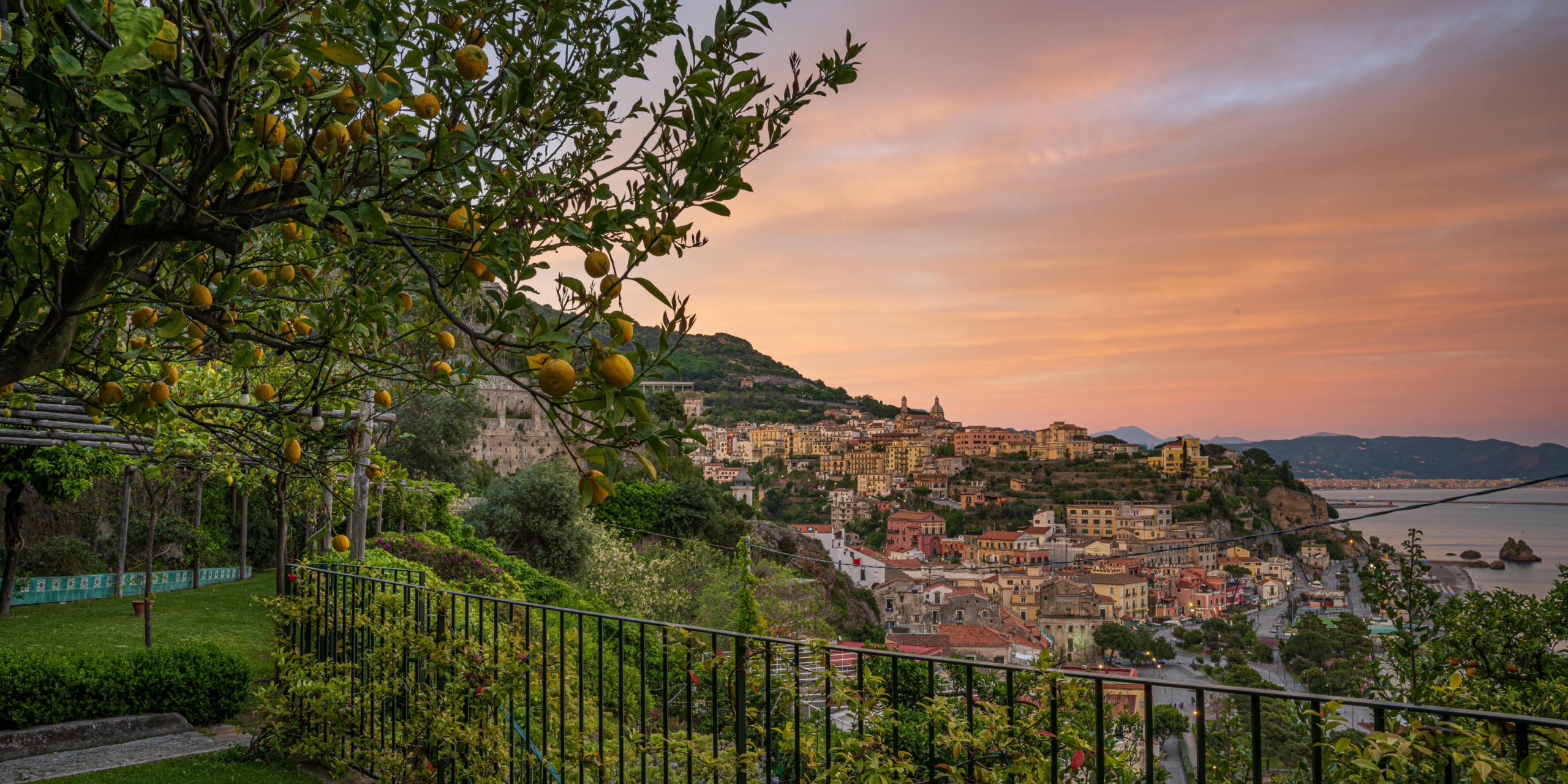 Sunset over Vietri sul Mare and the coast, seen from a garden terrace with a lemon tree and railing, Palazzo Suriano