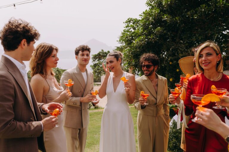 Guests with spritz glasses on the lawn during a wedding aperitivo, Pittalumari Makari