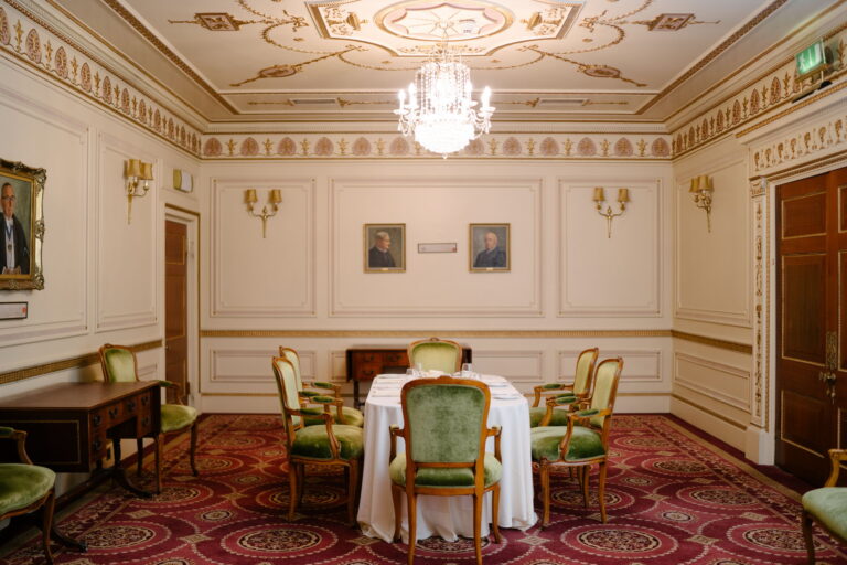 The Mott Room, a small panelled room with green upholstered chairs around a round table, Plaisterers' Hall