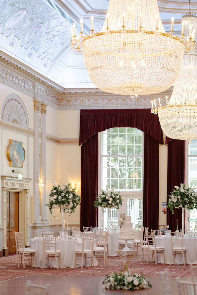 The Great Hall set for a wedding dinner, with chandeliers, draped windows and flowers on every table, Plaisterers' Hall