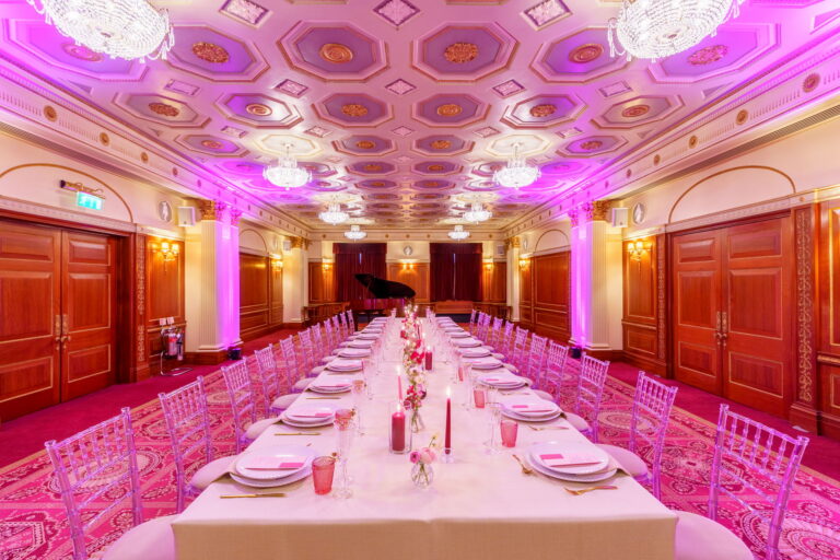 The Livery Hall with a long banquet table and a grand piano at the far end, lit in pink, Plaisterers' Hall