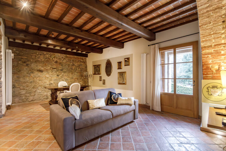 Suite living room with sofa, stone and brick walls, beamed ceiling and glazed doors, Relais La Costa