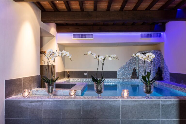 Indoor spa pool with mosaic tiles, orchids and candles under wooden beams, Relais La Costa