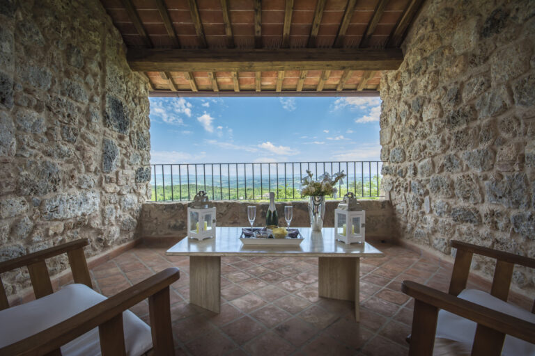 Covered stone loggia with seating and a wide view over the countryside, Relais La Costa