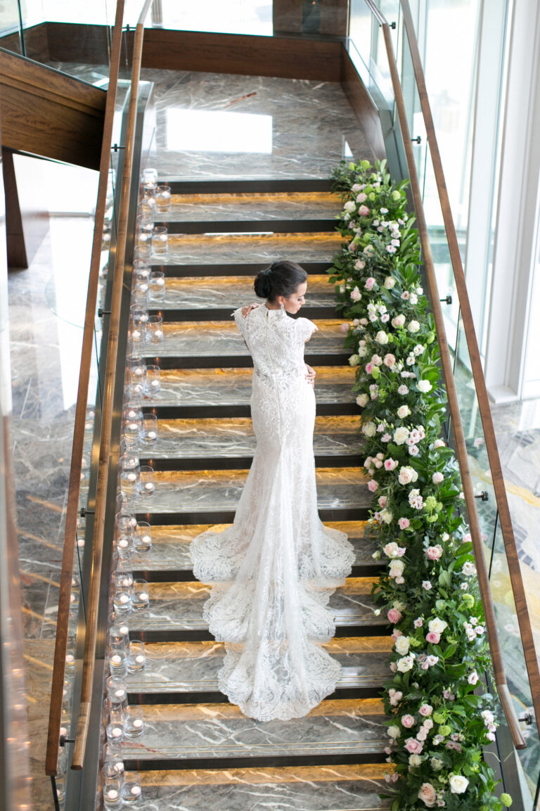 A bride on the grand staircase, its glass balustrade lined with white flowers, Shangri-La The Shard, London