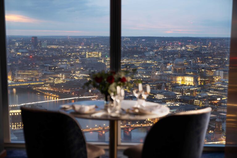 A table for two by the window at dusk, with St Paul's Cathedral and the river lit below, Shangri-La The Shard, London