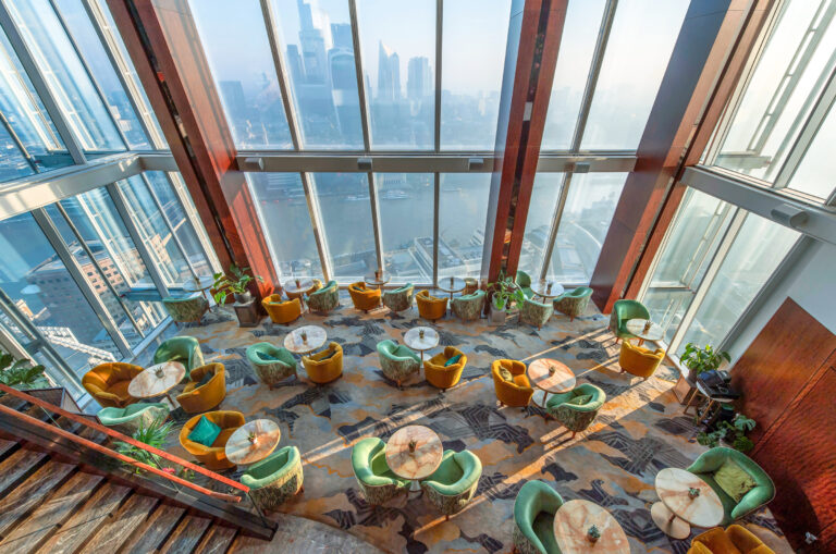 The lounge seen from the staircase above, with green and yellow armchairs under sloping glass walls, Shangri-La The Shard, London