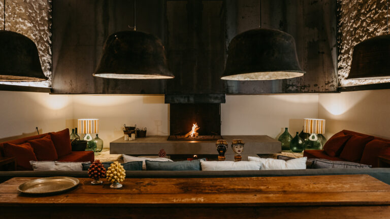 A lounge with sofas and pendant lamps around a lit fireplace, Susafa