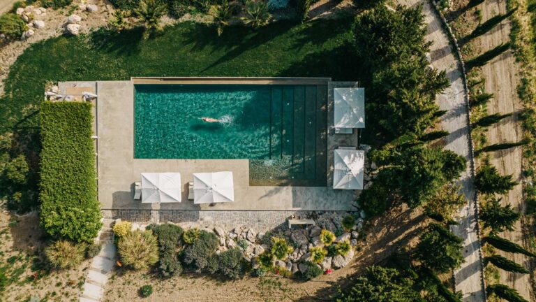 Overhead view of the pool, loungers and parasols framed by a hedge and garden, Susafa