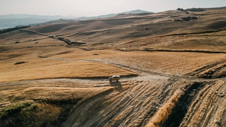 Aerial view of the rolling golden hills around Susafa, with a vehicle on a farm track, Susafa