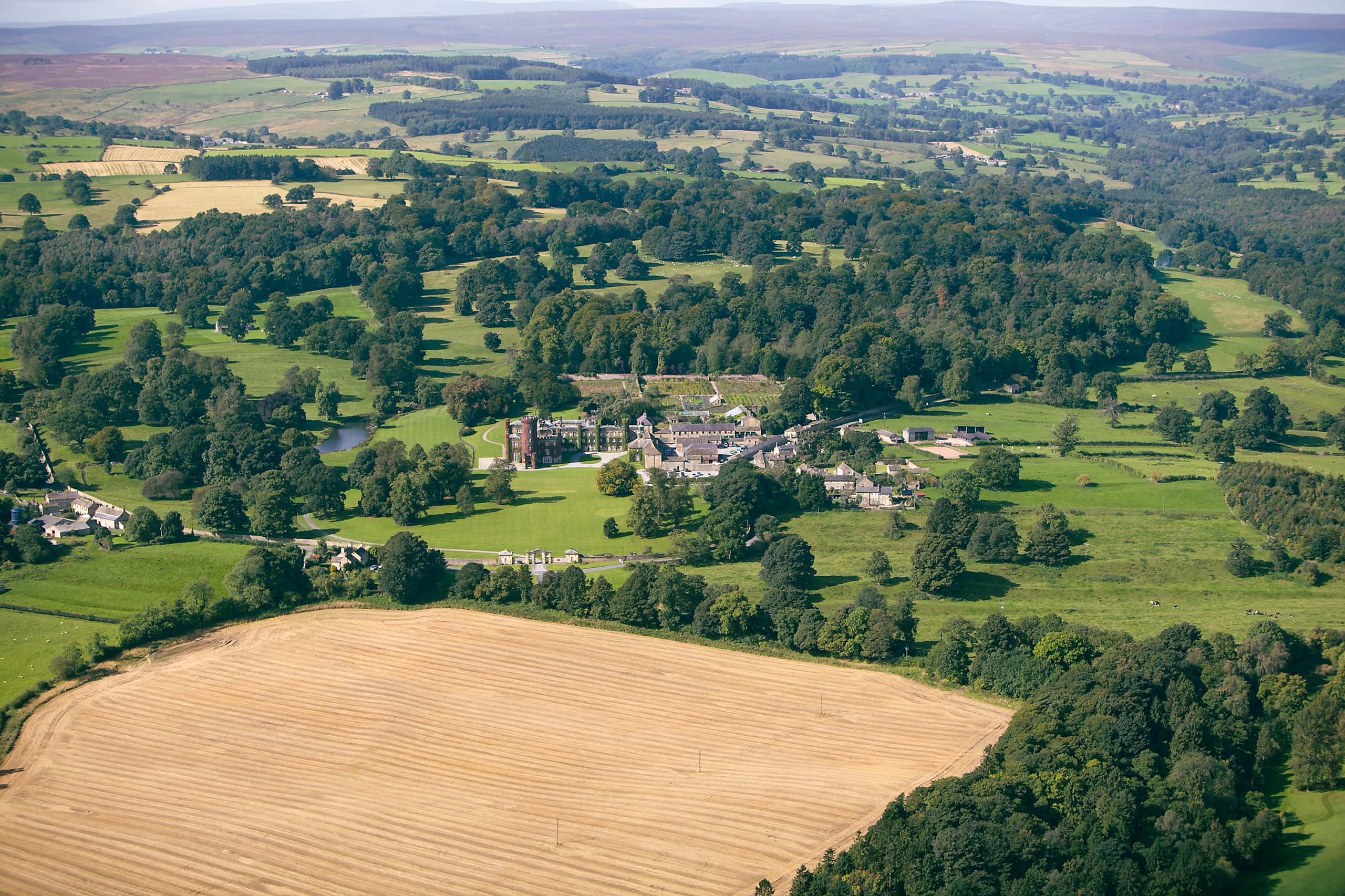 The wider estate from the air, with fields, woodland and the castle buildings in the middle distance, Swinton Park