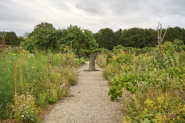 A gravel path through the walled kitchen garden in summer, with a sundial at its centre, Swinton Park