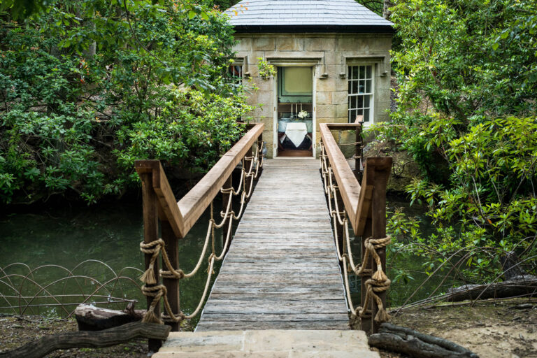 The footbridge leading to the Lake House, a small stone summerhouse among the trees, Swinton Park