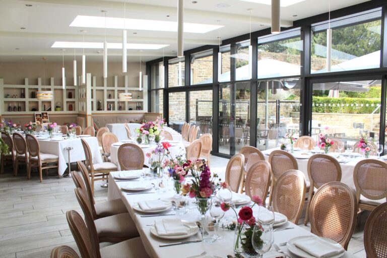 The glass-walled Terrace Restaurant set with long tables and flowers for a wedding meal, Swinton Park