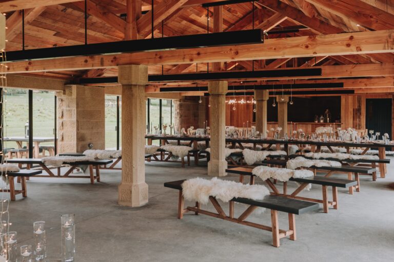 Inside the Deer House, long wooden tables and sheepskin-covered benches set out under the timber roof, Swinton Park