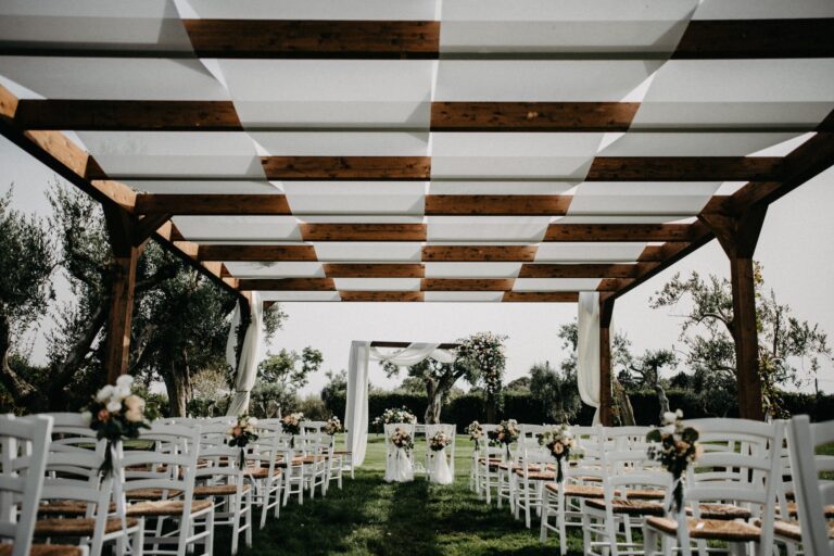 A ceremony set up with white chairs under a timber pergola facing the olive grove, Tenuta Pinto