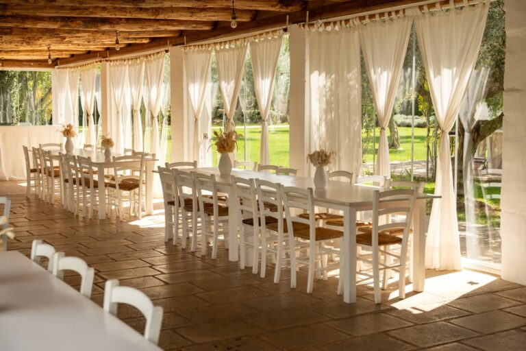 The covered pergola set with long tables behind white curtains, Tenuta Pinto