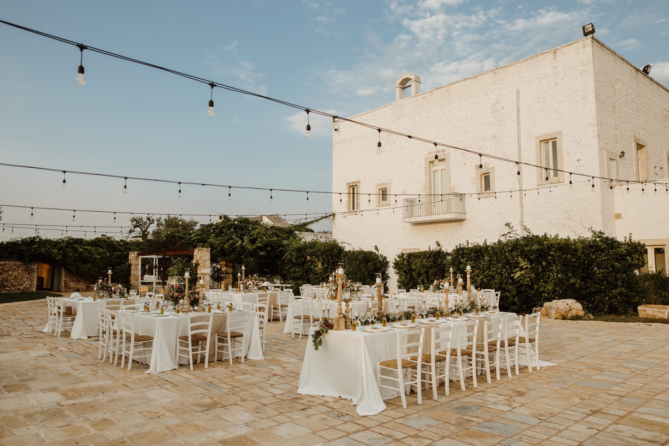 Tables laid on the stone-paved courtyard beside the masseria, Tenuta Pinto