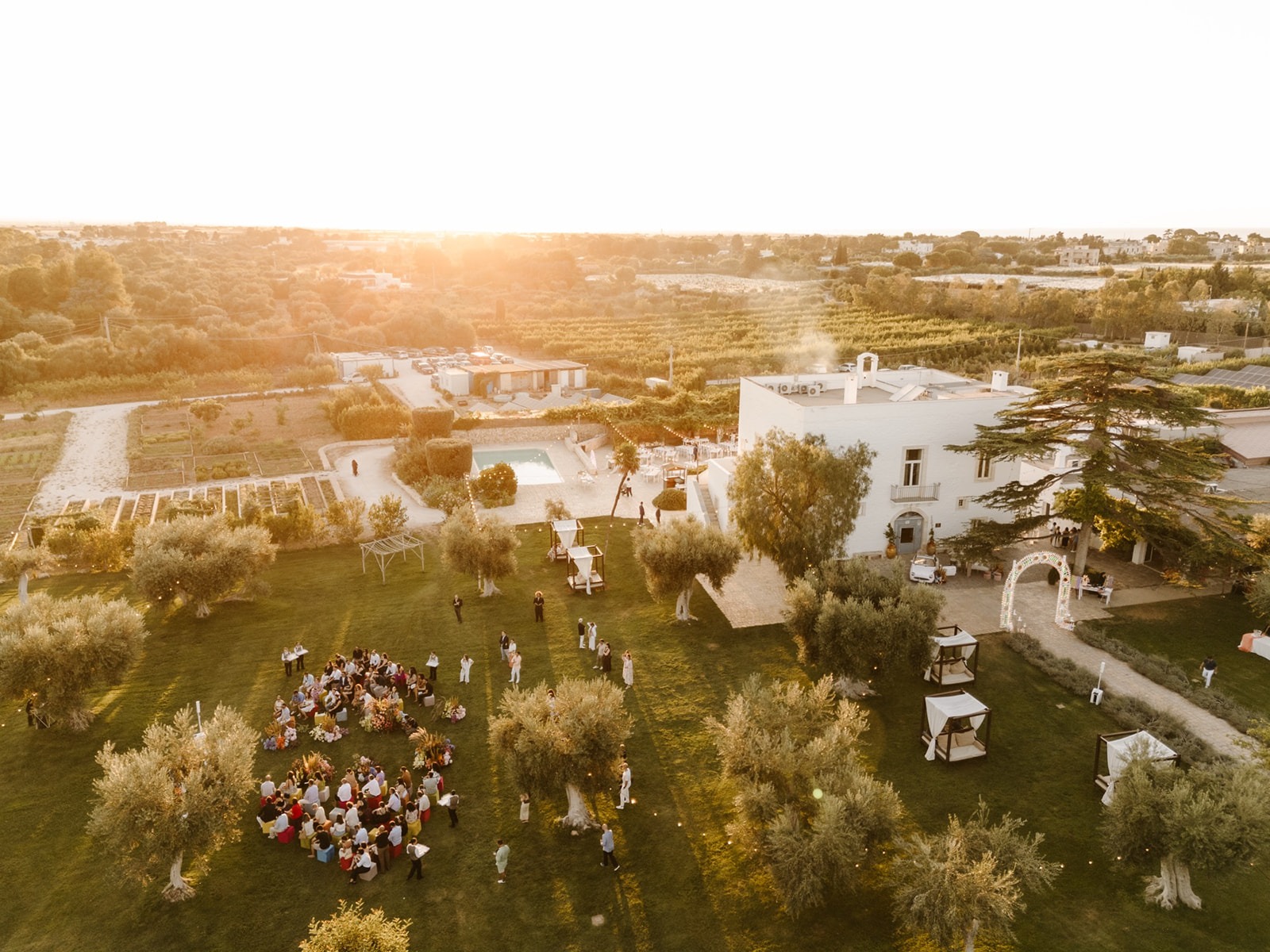 Aerial view of the masseria, pool, olive grove and farmland at sunset during an event, Tenuta Pinto