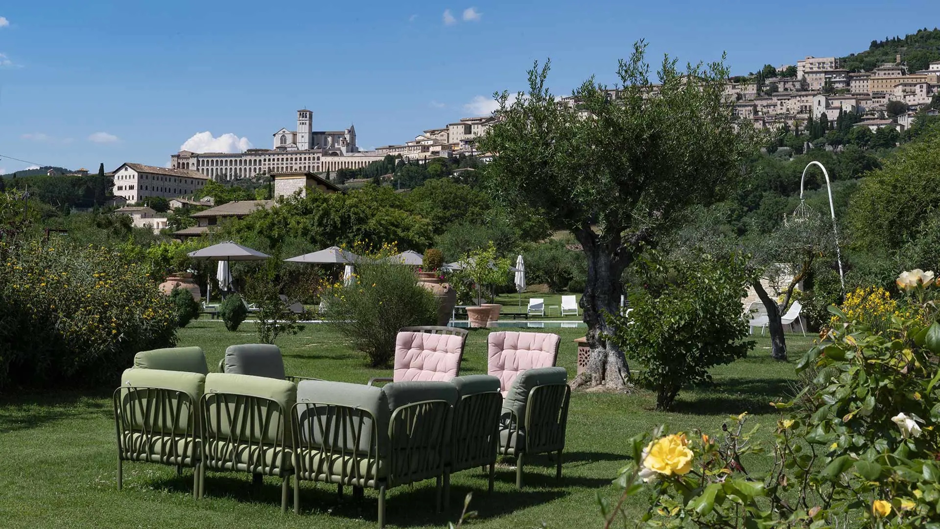 Garden lounge seating with Assisi and the Basilica of Saint Francis on the hill behind, Tenuta San Masseo