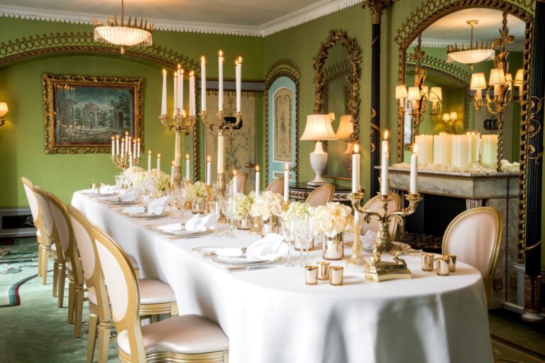 A candlelit table in the green-walled Pavilion with gilded mirrors and a fireplace, The Dorchester
