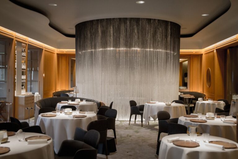The dining room of Alain Ducasse at The Dorchester with a curtain of glass fibre around a central table, The Dorchester