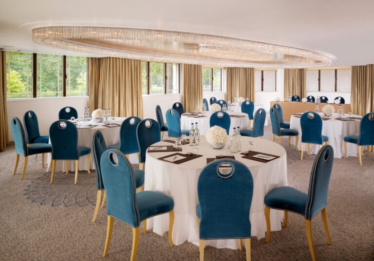 The Crystal Suite with round tables, blue chairs and a crystal chandelier, The Dorchester