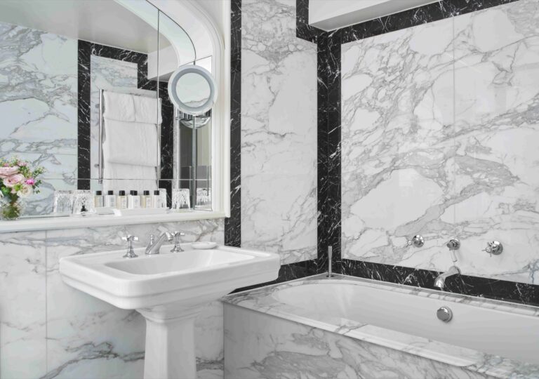 A white marble bathroom with a bath, pedestal basin and chrome fittings, The Goring