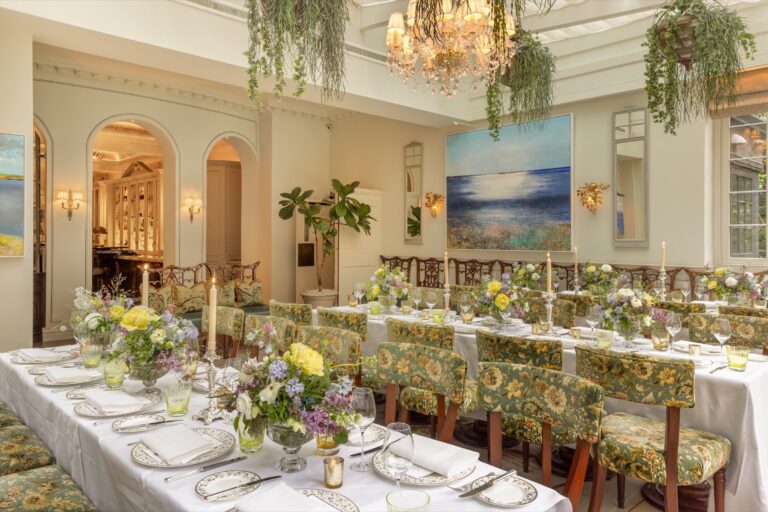 The Veranda laid for dinner, with floral chairs, candles and hanging greenery, The Goring