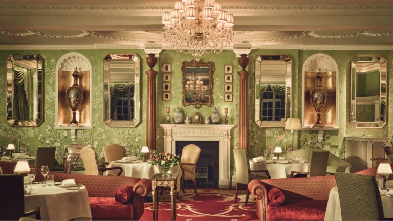 The Dining Room with green walls, mirrored panels, a fireplace and a crystal chandelier, The Goring