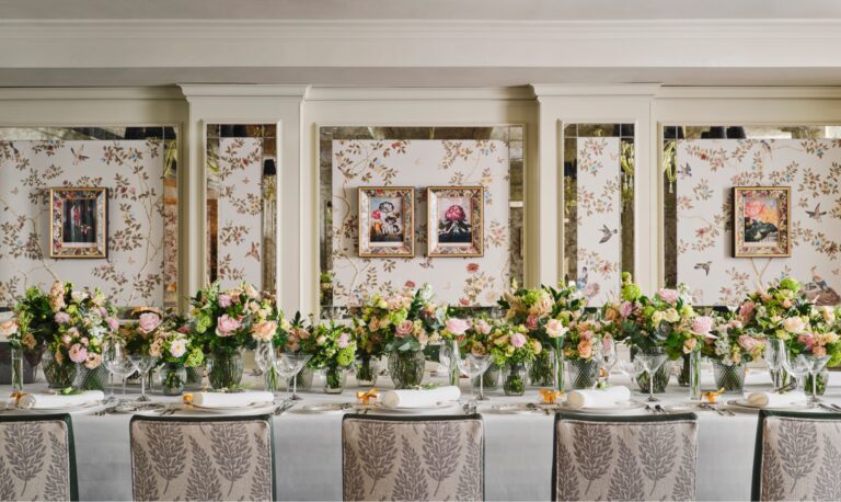 A long table lined with pink and white flowers in front of panelled walls hung with framed prints, The Goring