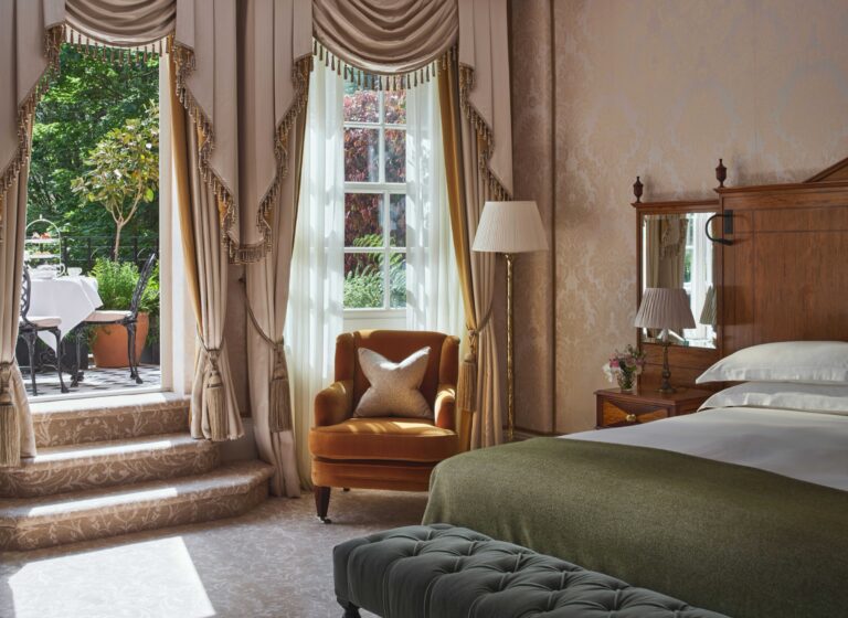 A Garden Junior Suite bedroom with an armchair and a door to a balcony over the garden, The Goring