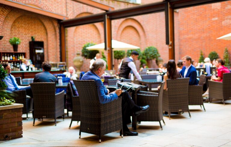 Diners at wicker tables in the Courtyard under a glazed roof, The Lansdowne Club