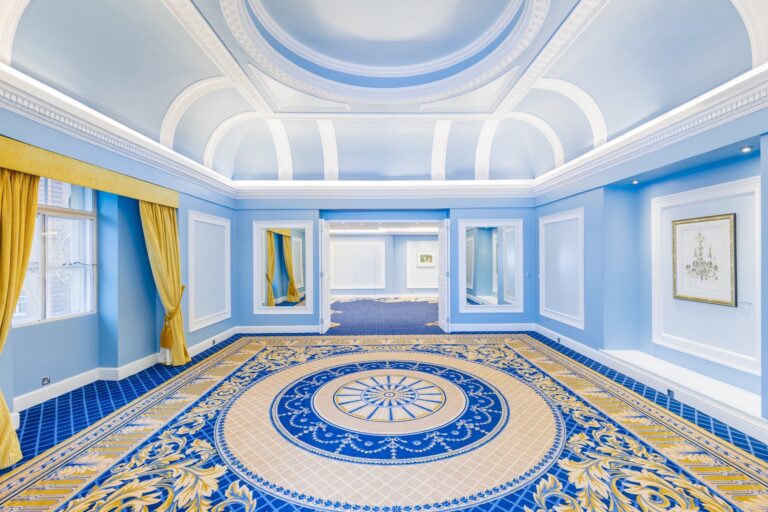The Shelburne Room empty, with pale blue walls, yellow curtains and a patterned carpet, The Lansdowne Club