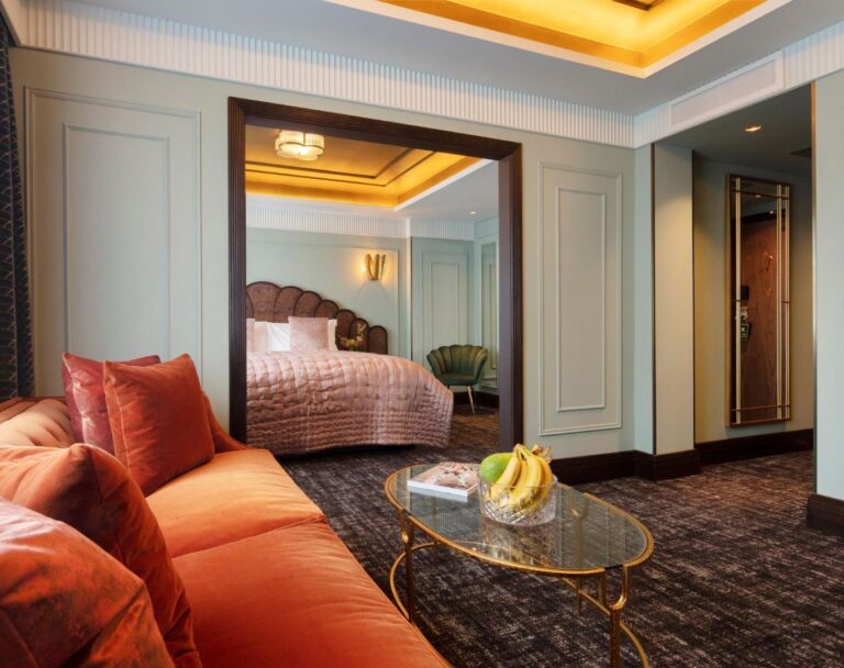 A suite sitting area with an orange velvet sofa, looking through to the bedroom, The Lansdowne Club