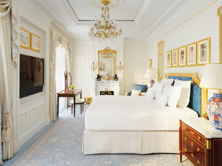 A Deluxe Room with a king-size bed, framed prints and blue cushions, The Ritz London