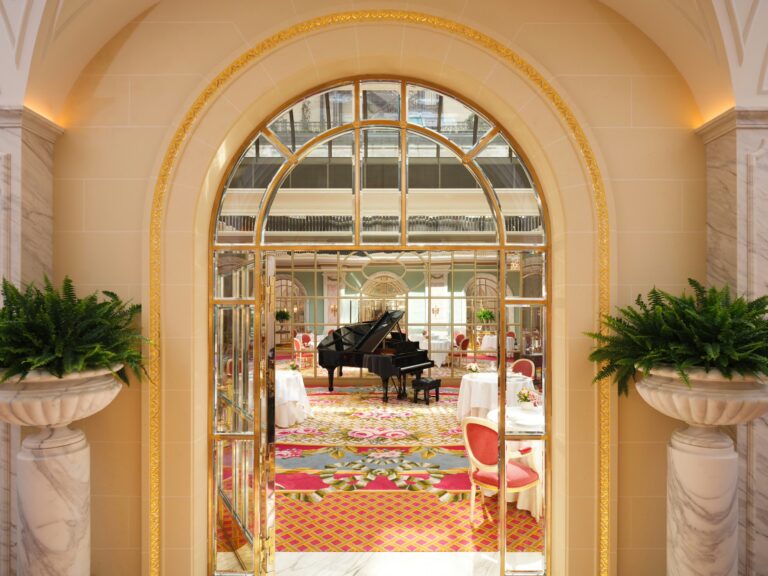An arched mirrored doorway looking into the restaurant, flanked by ferns in stone urns, The Ritz London