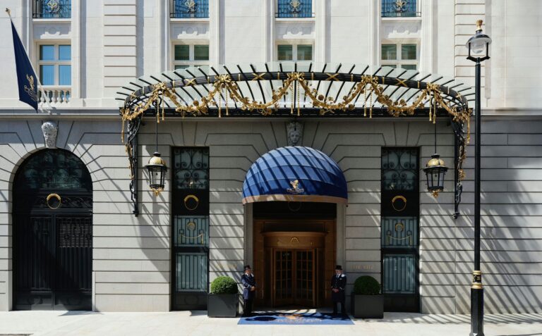 The hotel entrance under an iron and glass canopy, with a blue awning over the door, The Ritz London
