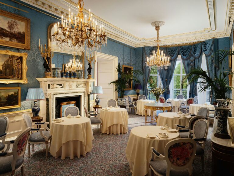 The Queen Elizabeth Room from the fireplace end, with round tables and gilt-framed paintings, The Ritz London
