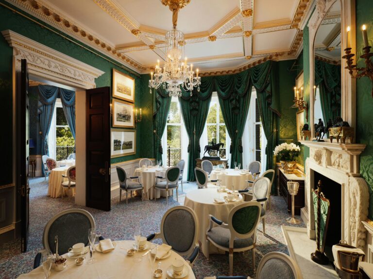 The Wimborne Room, with green curtains, a marble fireplace and tables laid for tea, The Ritz London